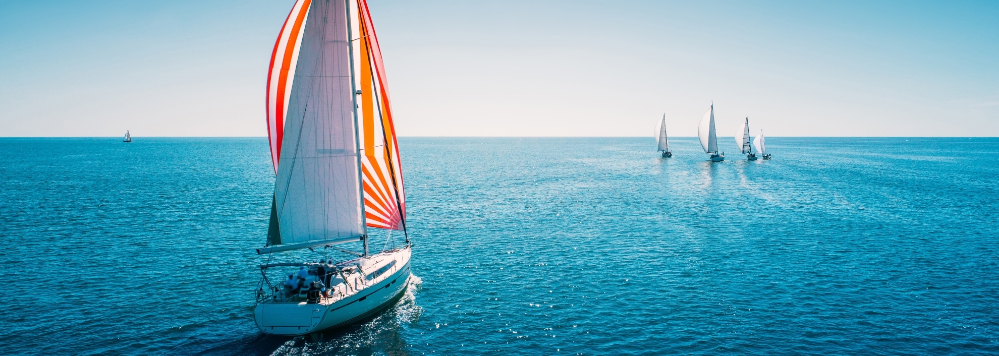 Close up of sailing Yacht with 5 more sailing yacts in the background