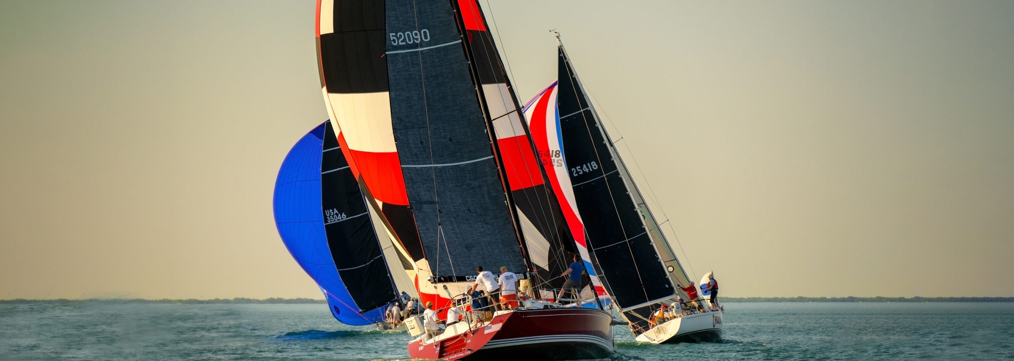 Three sailing yachts sailing off into distance